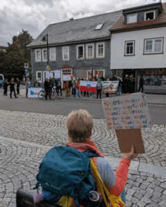 Gegen den CSD in Ilmenau (Thüringen), der 2025 zum ersten Mal stattfand und rund 400 Queers und Verbündete auf die Straße brachte, versammelte sich eine seltsame Mischung von Wutbürgern mit Bannern und Thüringenfahnen, Verschwörungsschwurbels mit kryptischen Pappschildern, Neonazihools in Naziklamotten und ressentimentgeladenen Passant*innen. (c) Queerantifa Thüringen